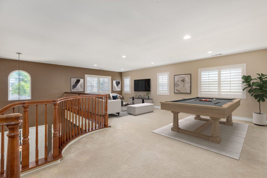 Spacious game room featuring a pool table, cozy seating area, and large windows, ideal for entertainment and relaxation.