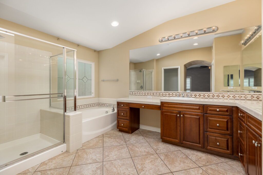 Spacious bathroom featuring a glass shower, large soaking tub, dual sinks, and ample natural light, perfect for relaxation and comfort.