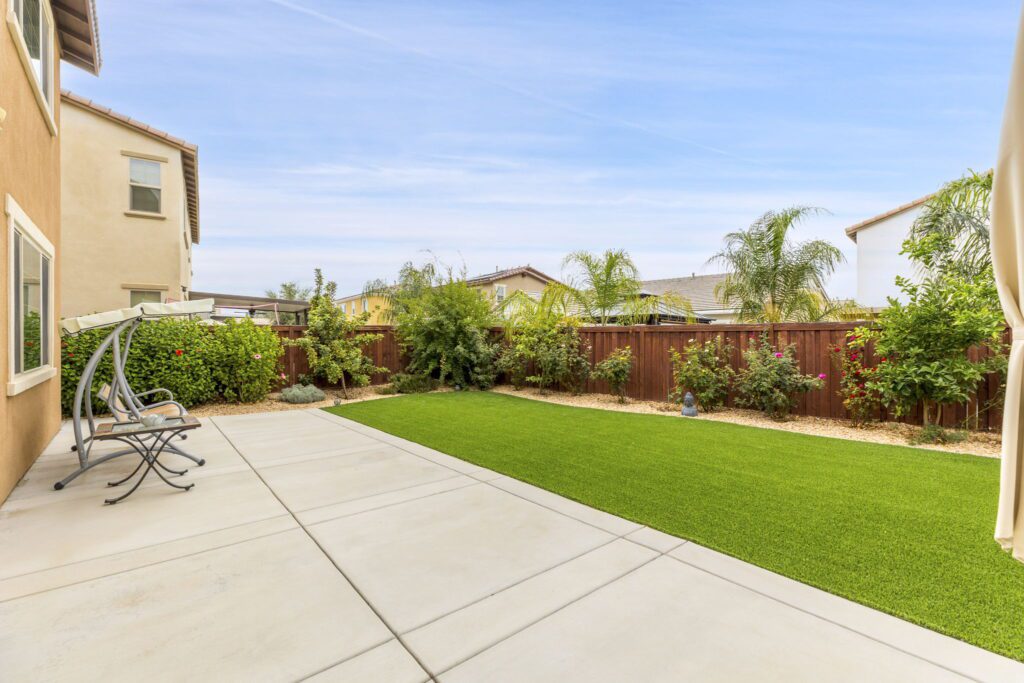 Backyard featuring a green lawn, colorful shrubs, and a relaxing seating area. Ideal for outdoor gatherings and leisure activities.