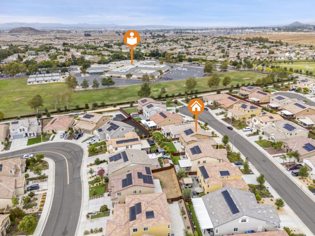 Aerial view of a suburban neighborhood featuring homes with solar panels, with icons indicating nearby schools and residential areas.