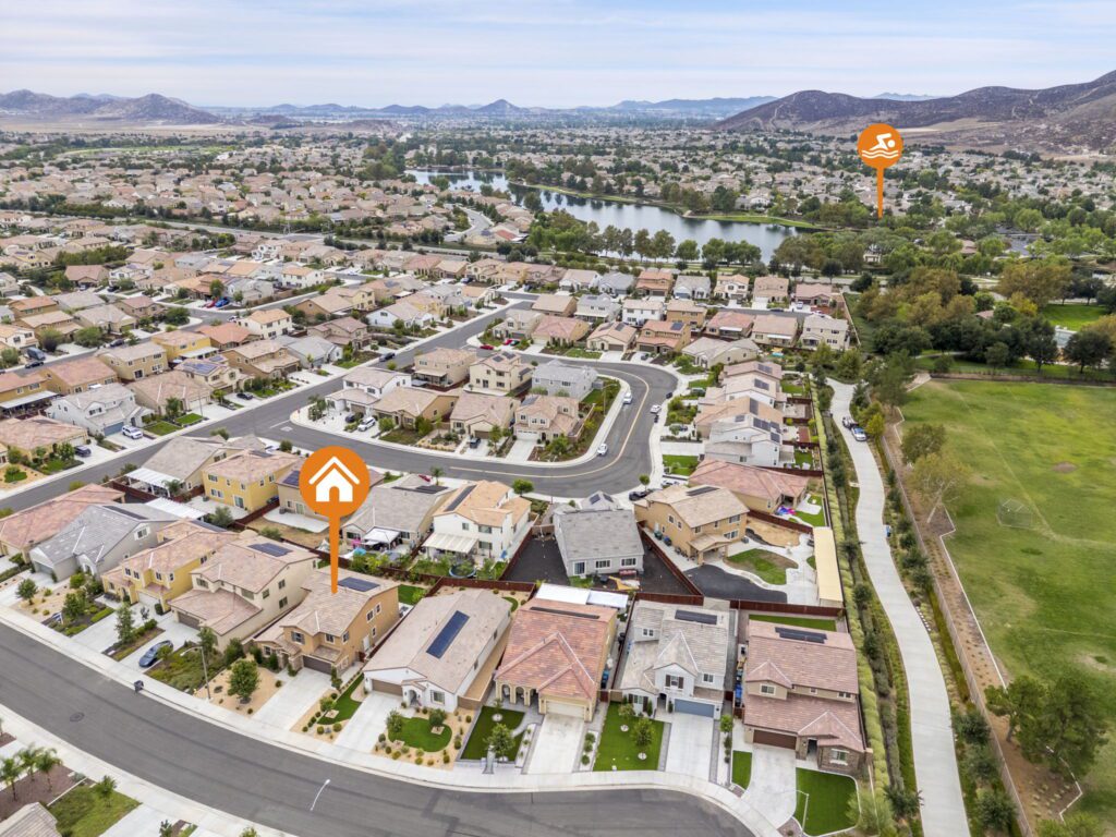 Aerial view of a suburban neighborhood with houses, streets, and a nearby lake, highlighting residential areas and green spaces.