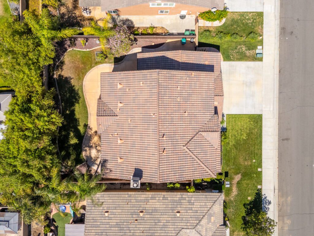 Aerial view of residential rooftops showcasing well-maintained gardens and driveways in a suburban neighborhood. Ideal for property analysis or neighborhood overviews.