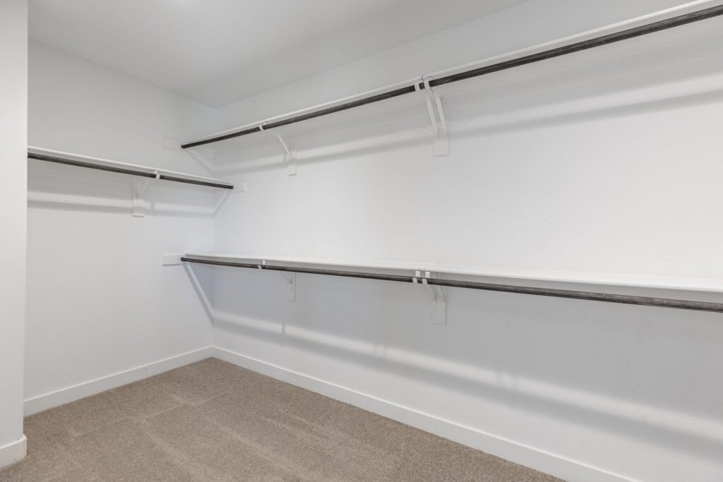 Spacious, empty closet featuring multiple shelves and hanging rods on white walls, showcasing potential storage options for organization.
