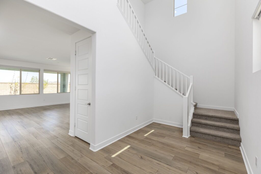 Bright entryway featuring a staircase leading to an upper level. Large windows provide natural light, enhancing the open space ambiance.