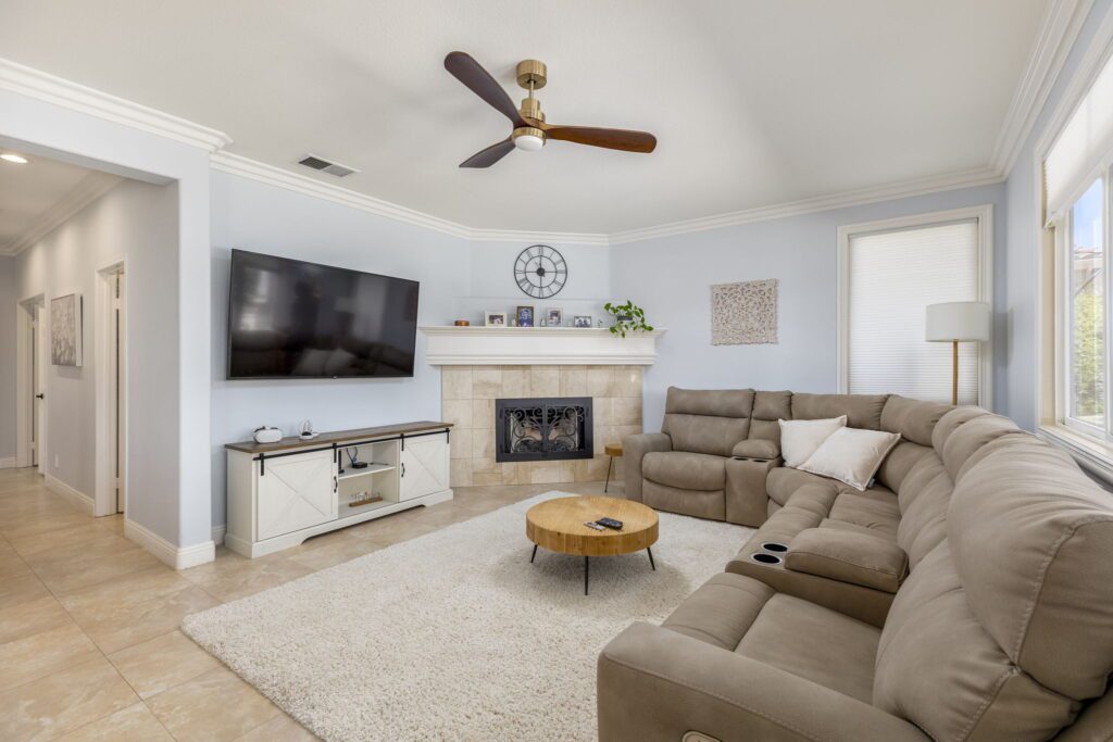 Cozy living room featuring a large sectional sofa, a round wood coffee table, mounted TV, and a decorative fireplace. Ideal for relaxation.