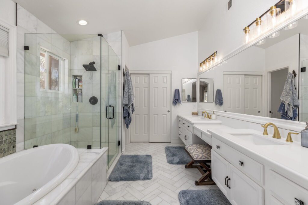 Modern bathroom featuring a glass shower, marble accents, double vanity, and decorative rug. Ideal for showcasing elegant design details.